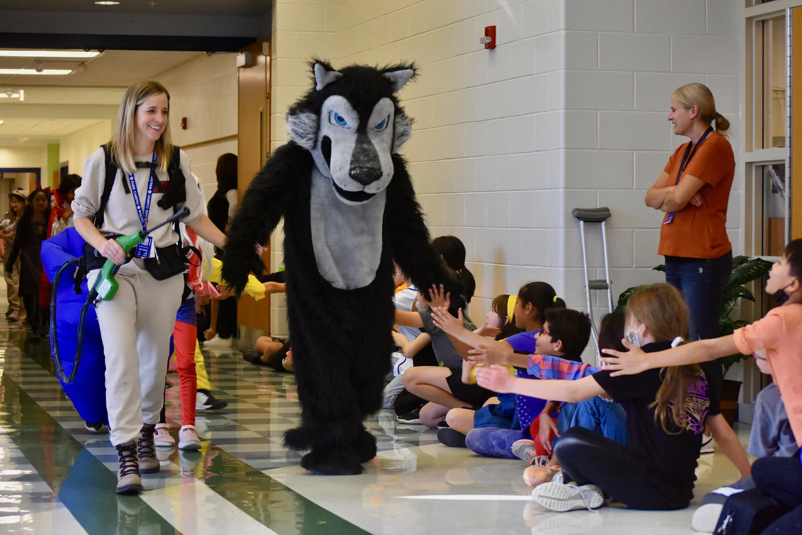 Park Campus Halloween Parade showing the PC mascot Wolfie high fiving students sitting in the hallway
