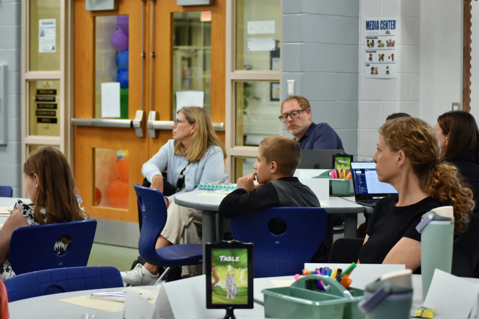 Members of the Strategic Planning committee listening while seated at tables in the Media Center at Park Campus