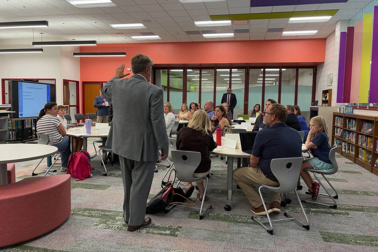 Members of the Portrait of a Learner team sitting in groups at tables listening to the presenter