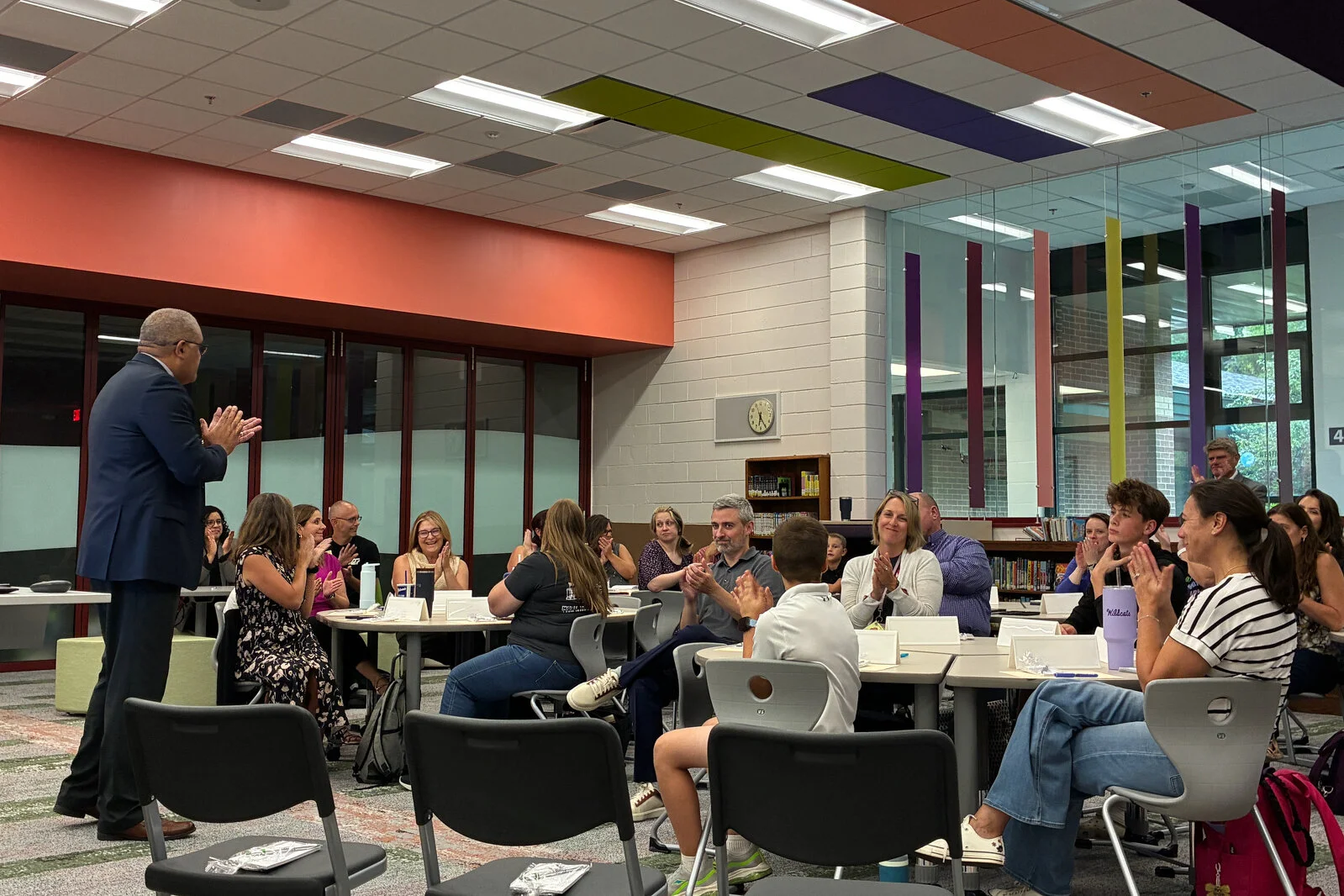 Members of the Portrait of a Learner team sitting in groups at tables listening to the Superintendent
