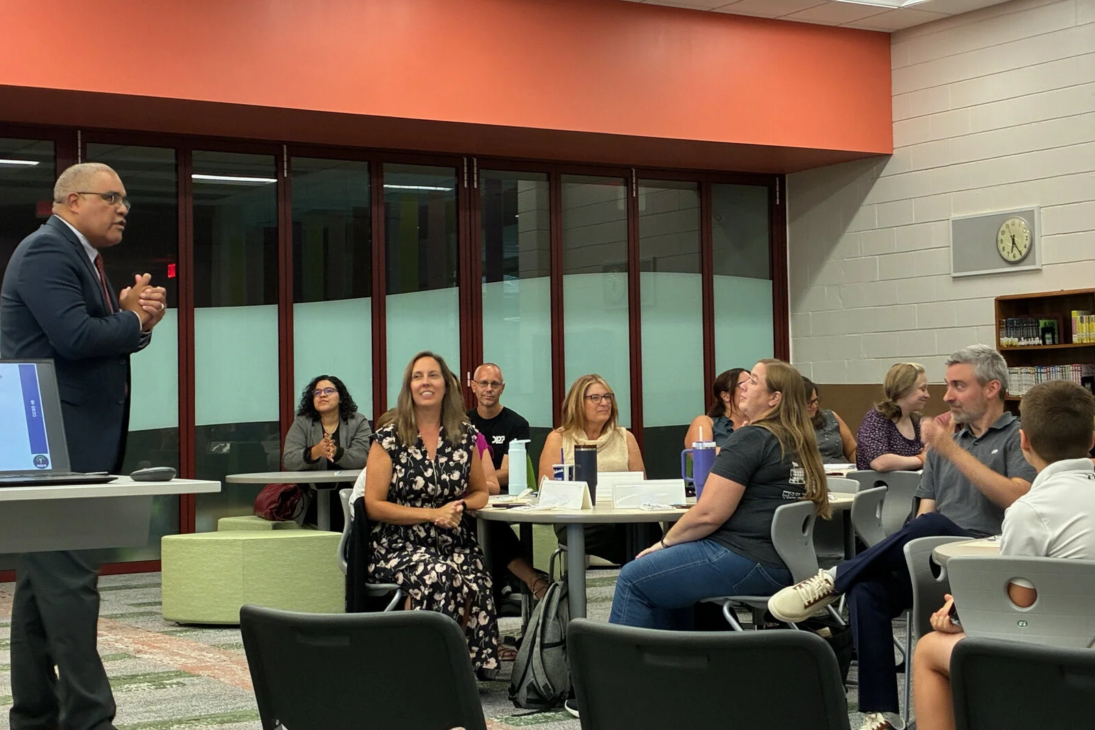 Members of the Portrait of a Learner team sitting in groups at tables listening to the Superintendent